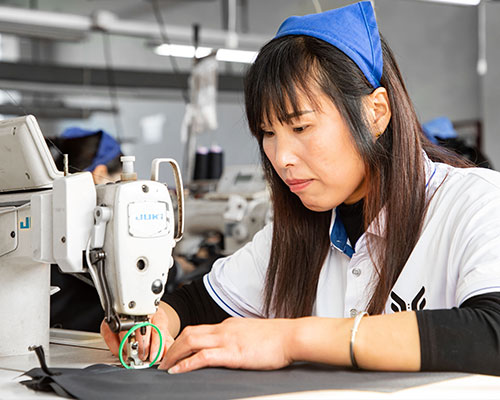 A woman is seaming parts together to make a jacket