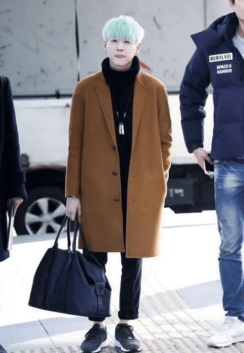 Suga of BTS wearing a tan oversized coat